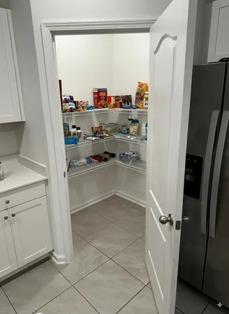 a view of storage and utility room with refrigerator and window