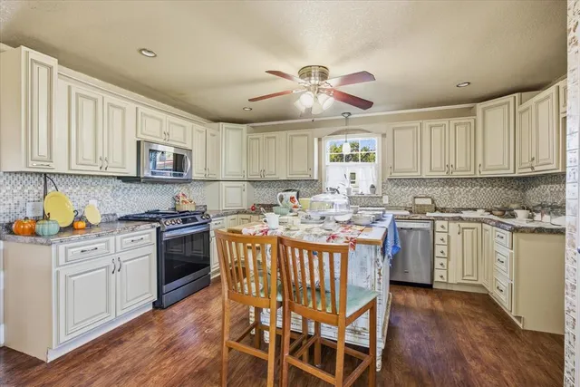 a kitchen with kitchen island granite countertop wooden floors and white cabinets