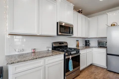 a kitchen with granite countertop white cabinets and stainless steel appliances