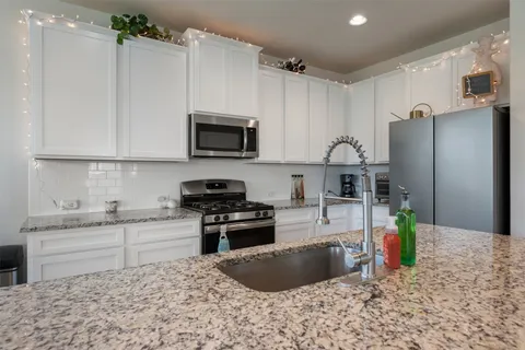 a kitchen with stainless steel appliances granite countertop a refrigerator sink and stove