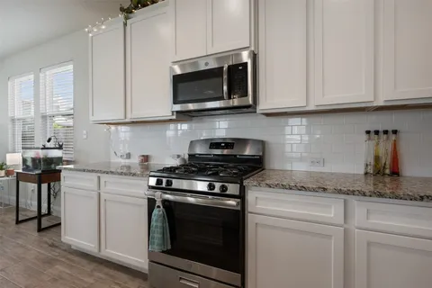a kitchen with stainless steel appliances granite countertop white cabinets granite counter tops and a wooden floors