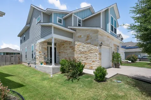 a view of a white house next to a yard with big trees