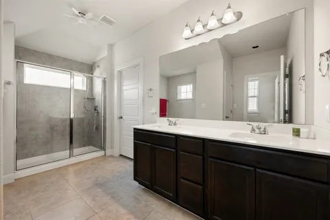 a bathroom with a double vanity sink mirror and shower