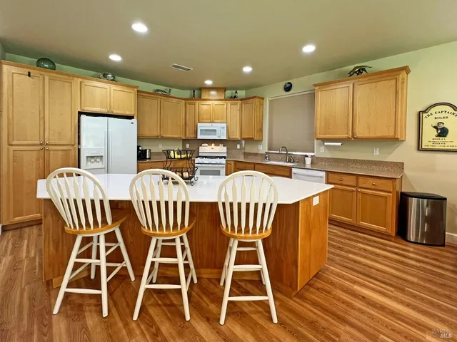 a view of a kitchen with a dining table chairs wooden cabinets and wooden floor