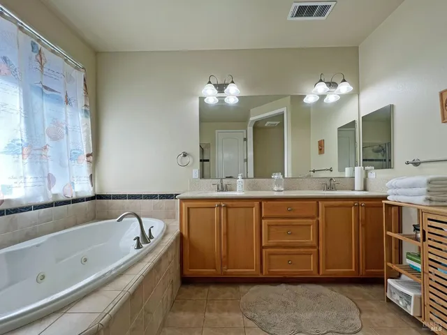 a bathroom with a tub sink double vanity and a mirror