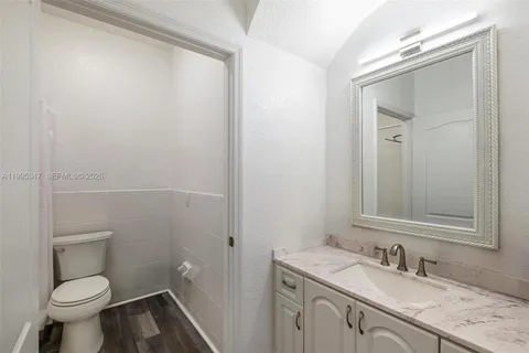 a bathroom with a granite countertop sink toilet and a mirror