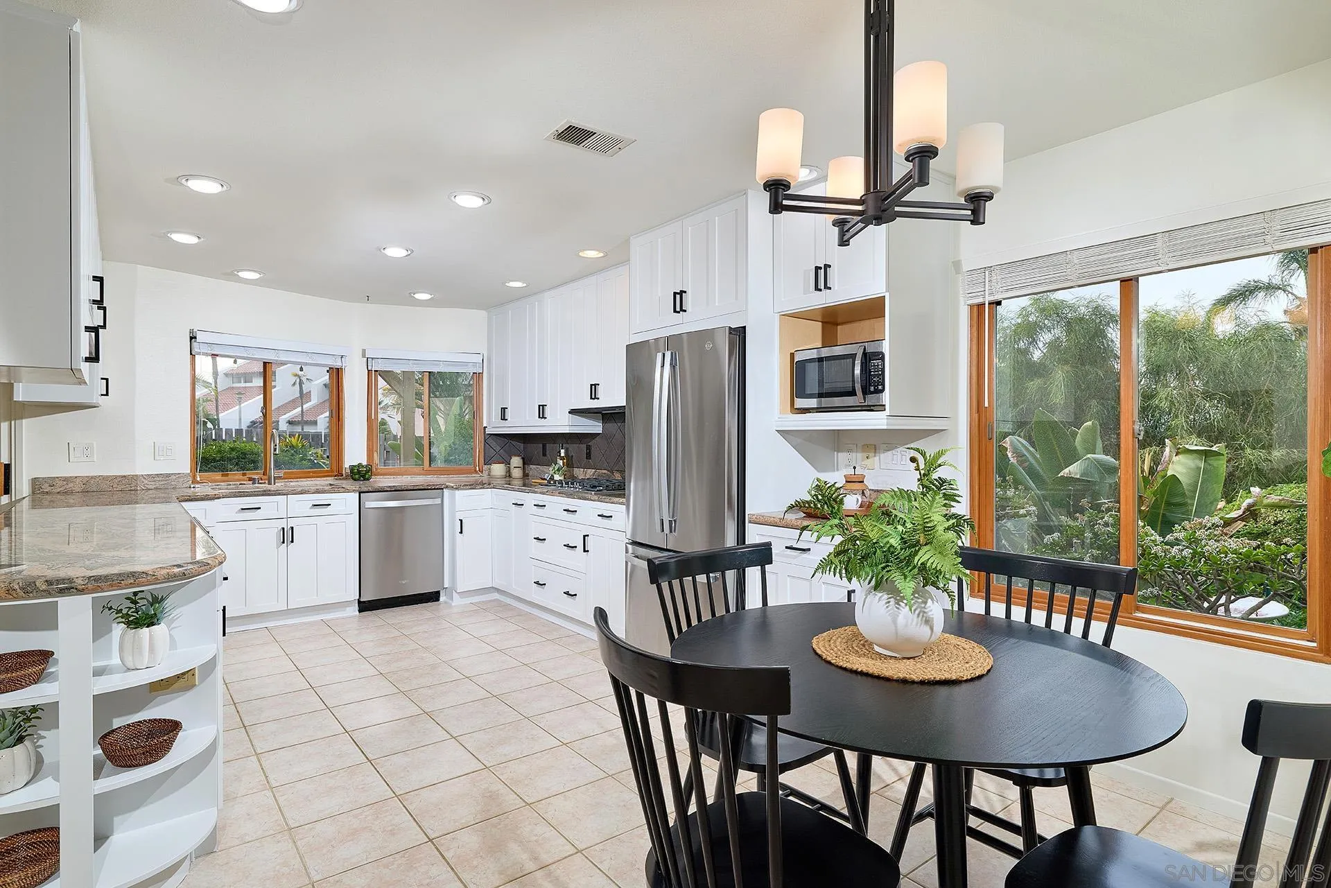 7627 Reposado Drive Carlsbad, CA 92009 - Photo 8 of 54 a kitchen with stainless steel appliances kitchen island granite countertop a dining table chairs and granite counter tops