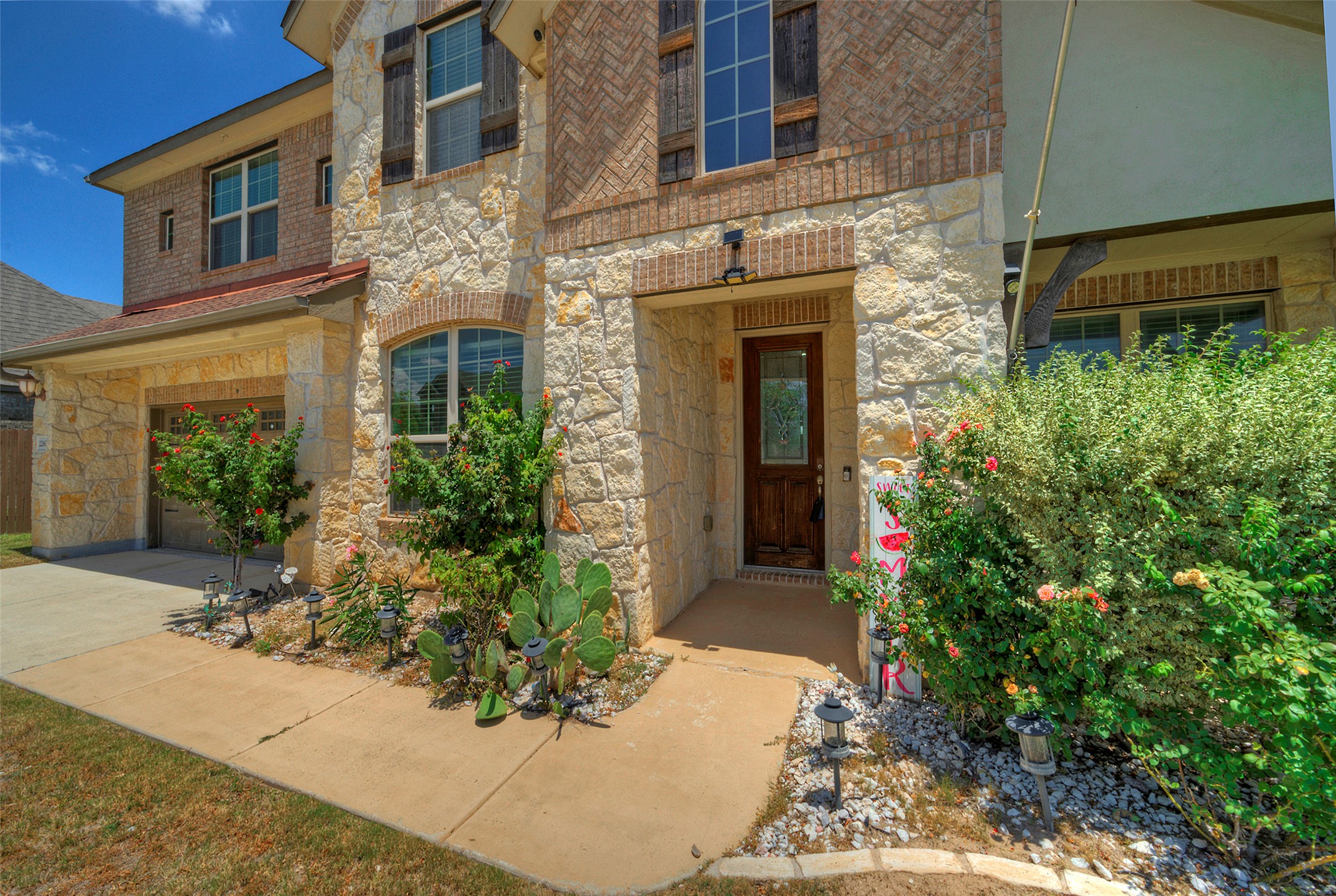 2260 Hat Bender Loop Round Rock, TX 78664 - Photo 3 of 40 A stone and brick facade with a welcoming wooden door frames a well-maintained front yard.
