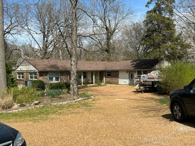 a view of a house with large trees and sitting area