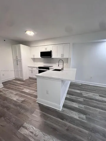 a large white kitchen with kitchen island a sink stainless steel appliances and cabinets