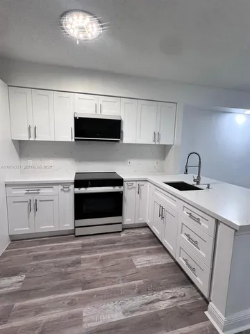 a kitchen with granite countertop a stove a sink and a microwave