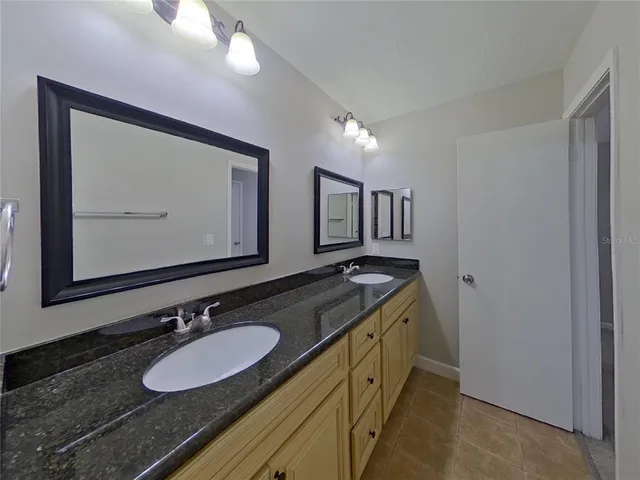 a bathroom with a granite countertop double vanity sink and a mirror