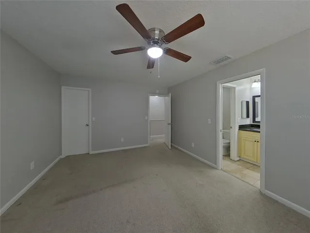 an empty room with closet and a ceiling fan