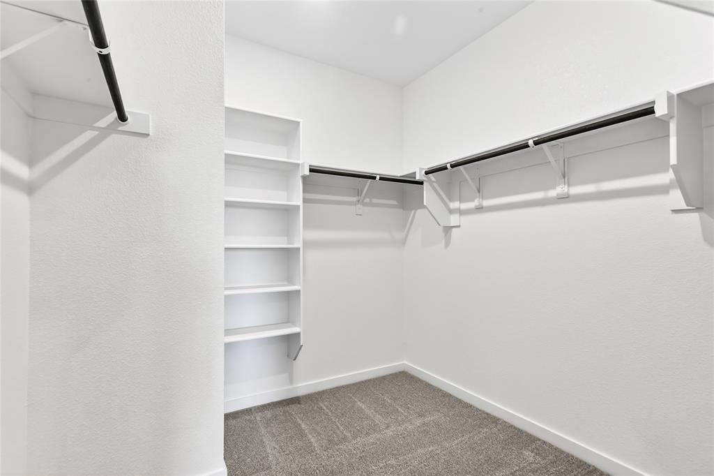 656 Waymaker Way Princeton, TX 75407 - Photo 33 of 40 Walk-in closet featuring built-in shelving, multiple hanging rods, white walls, white baseboards, and carpet flooring