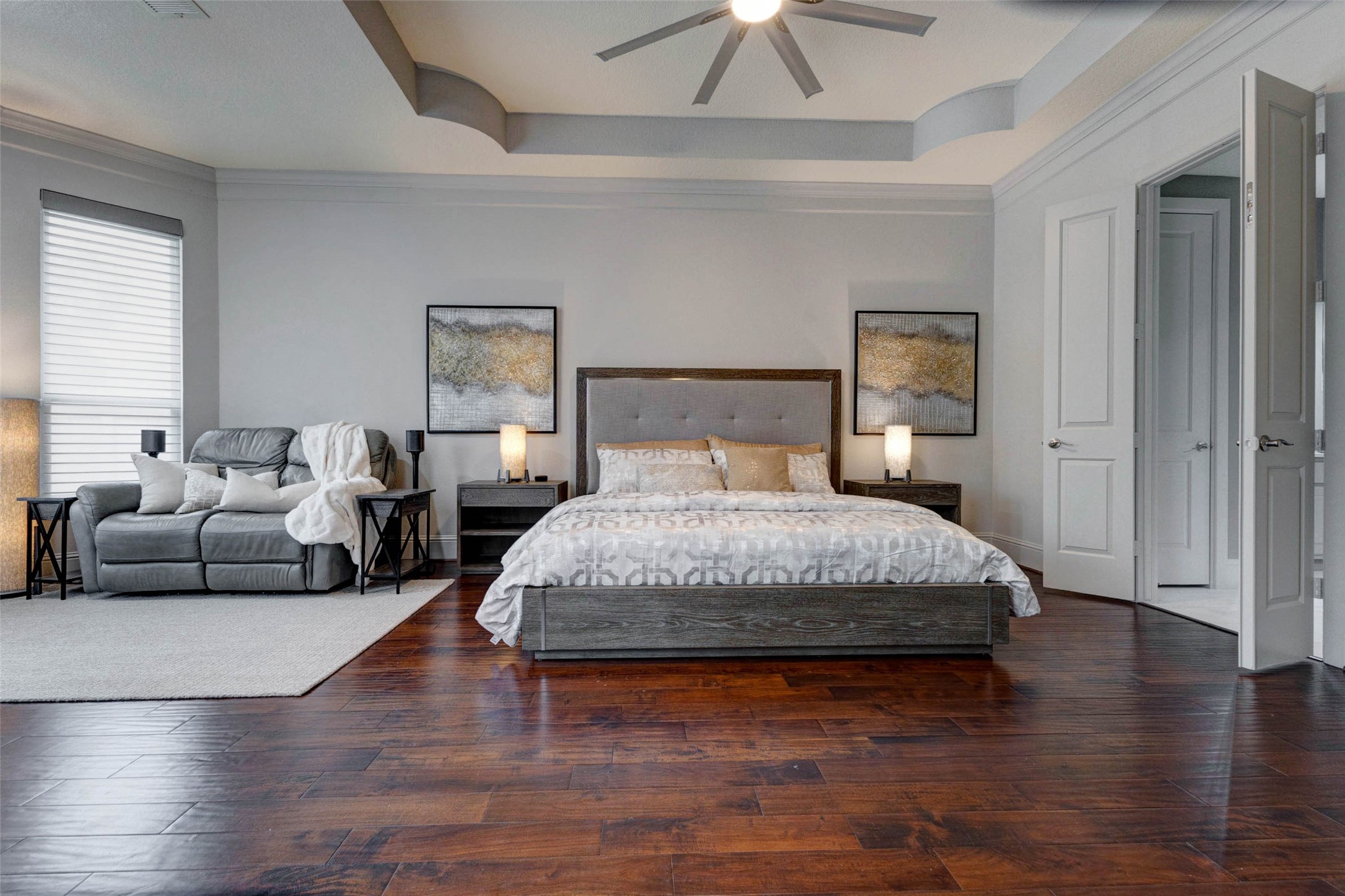 27602 Guthrie Ridge Lane Katy, TX 77494 - Photo 20 of 50 The expansive primary suite provides a warm and comfortable escape, highlighted by tray ceilings, rich hardwood flooring, and a private sitting area perfect for unwinding, complete with a 55" Samsung Smart LED TV (not shown) positioned across from the couch.