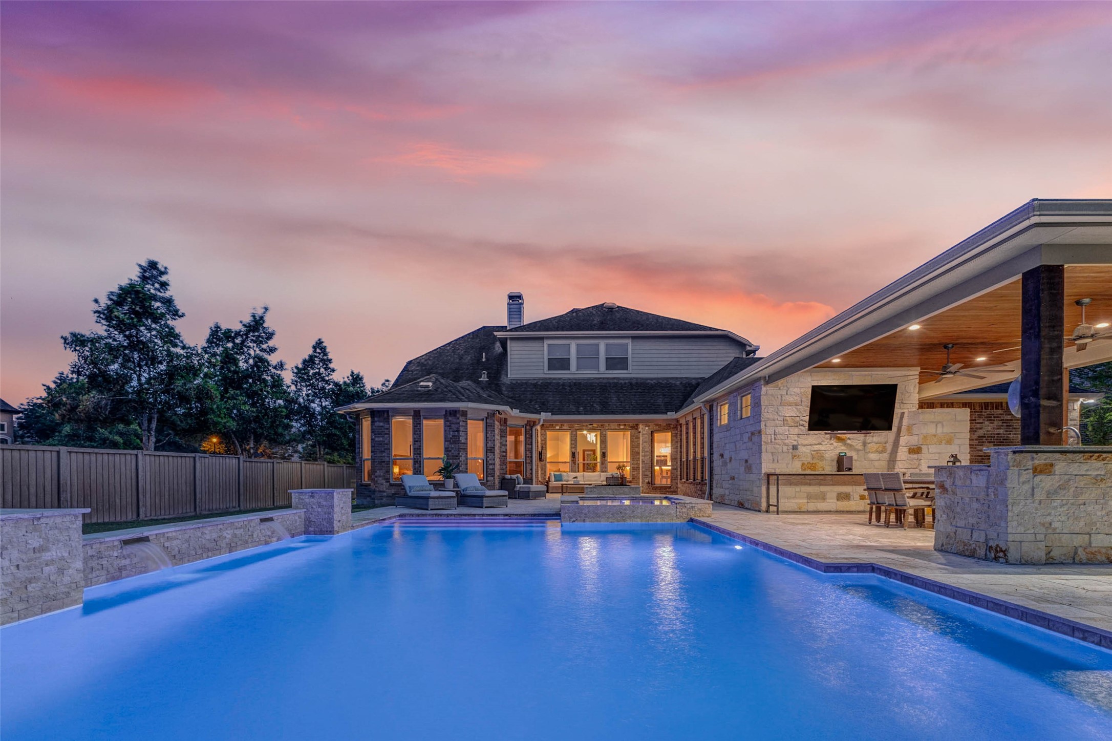 27602 Guthrie Ridge Lane Katy, TX 77494 - Photo 47 of 50 As evening sets in, the backyard takes on a warm glow, where the softly illuminated water feature creates a cozy gathering space perfect for hosting or unwinding after dark.