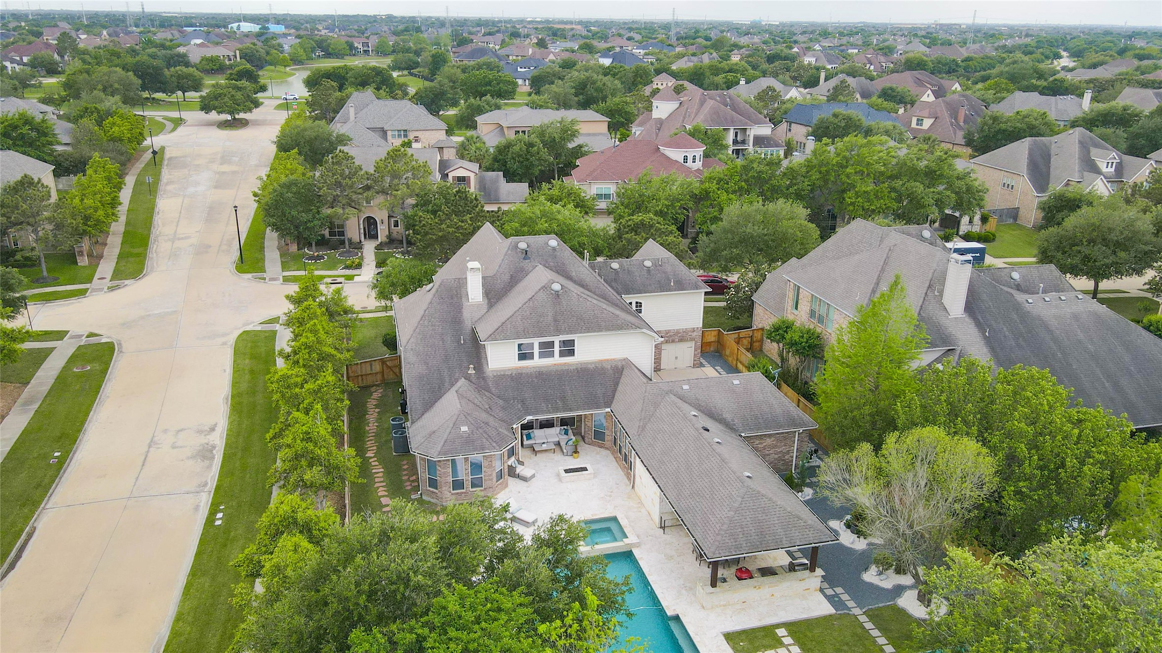 27602 Guthrie Ridge Lane Katy, TX 77494 - Photo 49 of 50 An elevated view highlights a well-balanced outdoor retreat, featuring a custom pool and spa, fire pit, entertaining areas, curated stone garden, and private basketball court. A rare combination of recreation, relaxation, and seclusion.