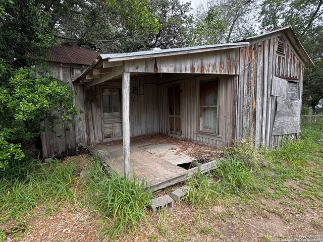 a view of a small house with roof and wooden fence