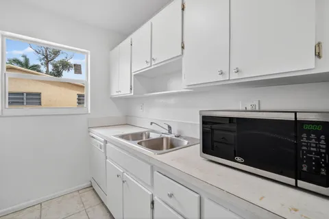 a kitchen with white cabinets and sink