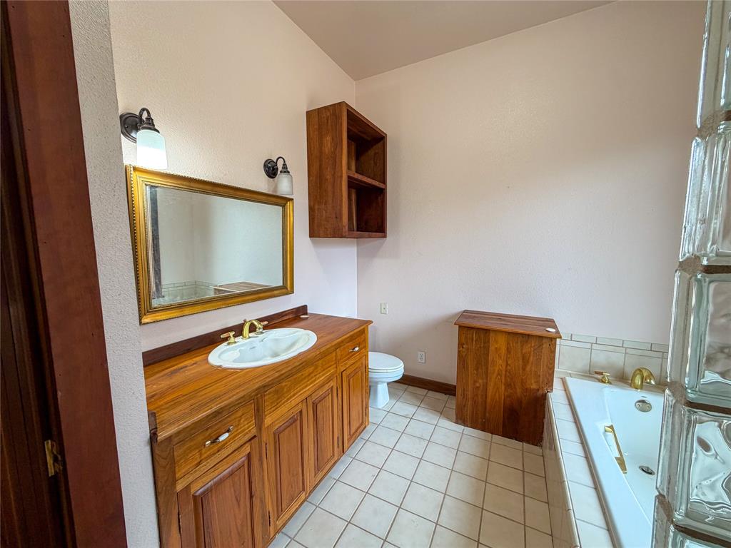 322 Wild Wood Drive Decatur, TX 76234 - Photo 26 of 39 a bathroom with a toilet mirror vanity and sink