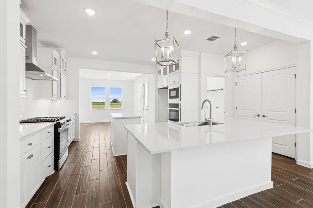 a kitchen with stainless steel appliances a stove a sink a center island and cabinets