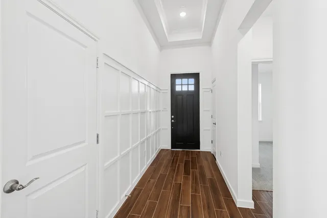 a view of a hallway with wooden floor and a bathroom