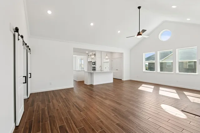a view of an empty room with a window and wooden floor