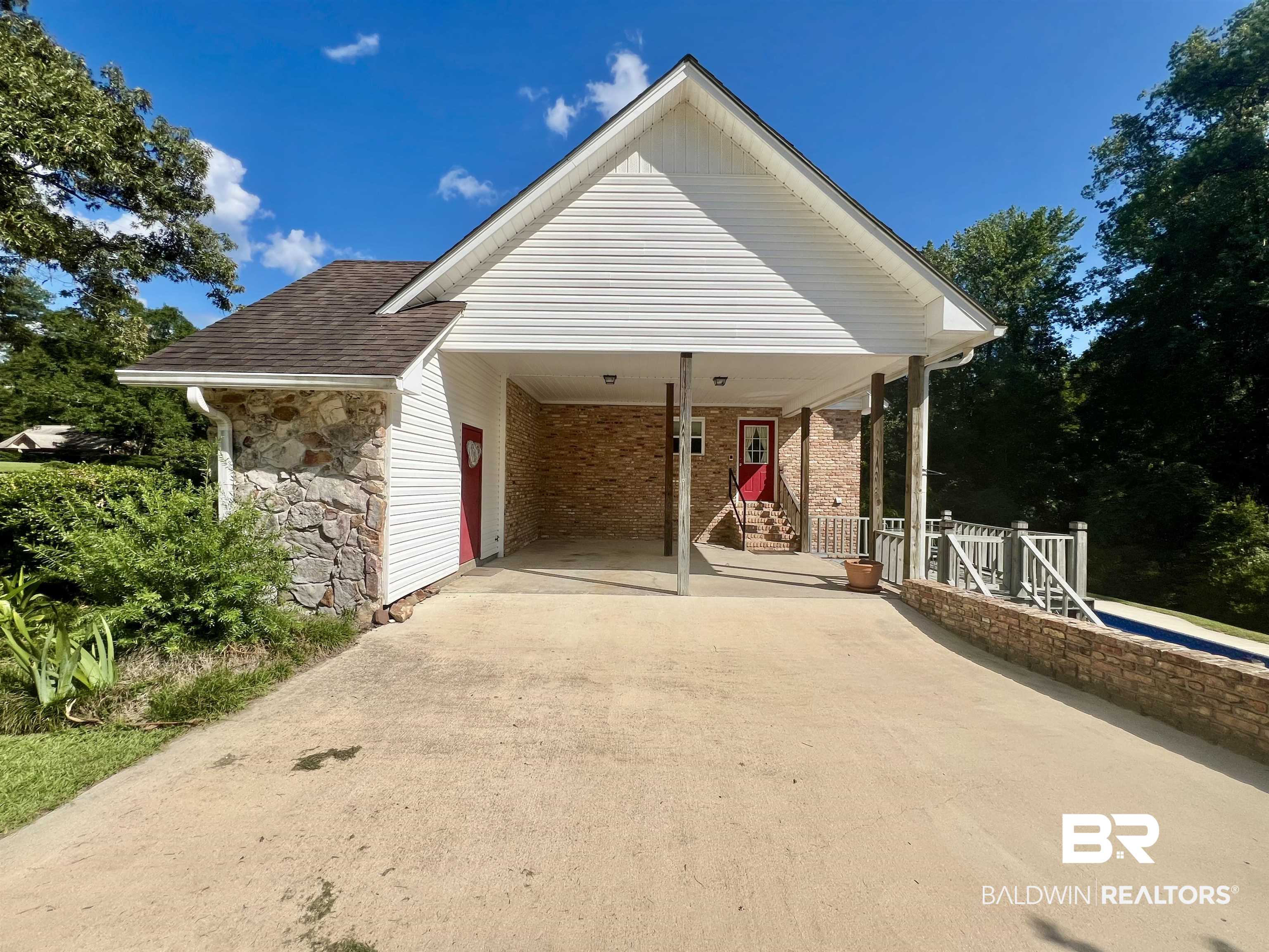 2691 Appleton Road Brewton, AL 36426 - Photo 5 of 60 View of front of home with driveway, stone siding, a patio area, roof with shingles, and a carport