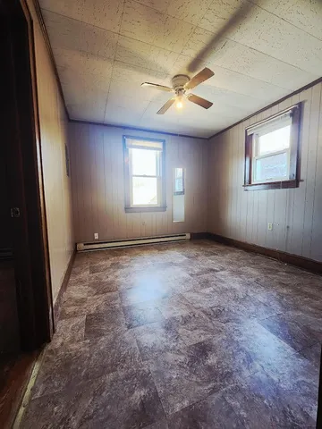 an empty room with windows and fan