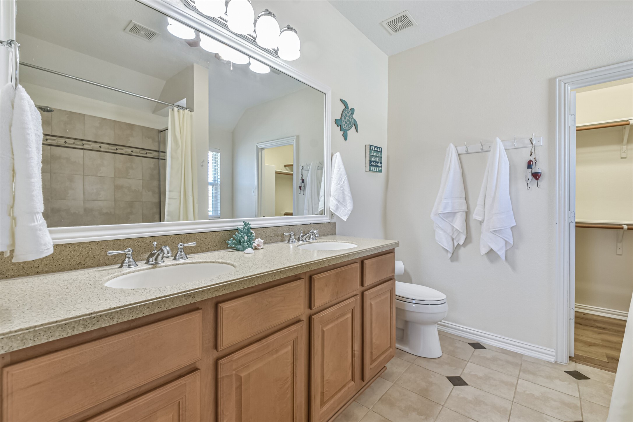 1815 28th Street Galveston, TX 77550 - Photo 15 of 42 This bathroom features a spacious double vanity with ample storage, modern fixtures, and a large mirror. It includes a shower with a curtain, neutral tile flooring, and convenient access to a walk-in closet.