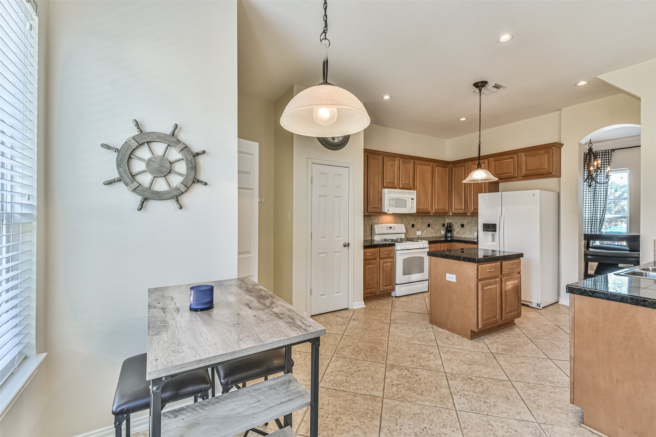 1815 28th Street Galveston, TX 77550 - Photo 31 of 42 Bright and inviting kitchen with light wood cabinetry, granite countertops, and modern appliances. Features a cozy breakfast nook, tile flooring, and nautical decor. Ideal for casual dining and entertaining.
