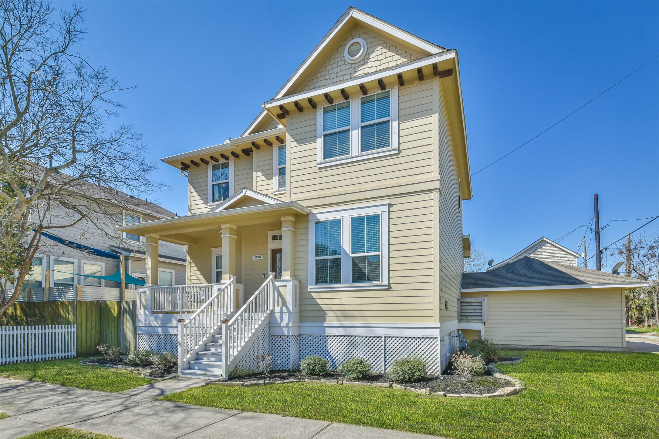 1815 28th Street Galveston, TX 77550 - Photo 38 of 42 Charming two-story yellow house with a welcoming front porch, white trim, and a neatly landscaped yard. Features a detached garage and a side driveway, perfect for a family home.