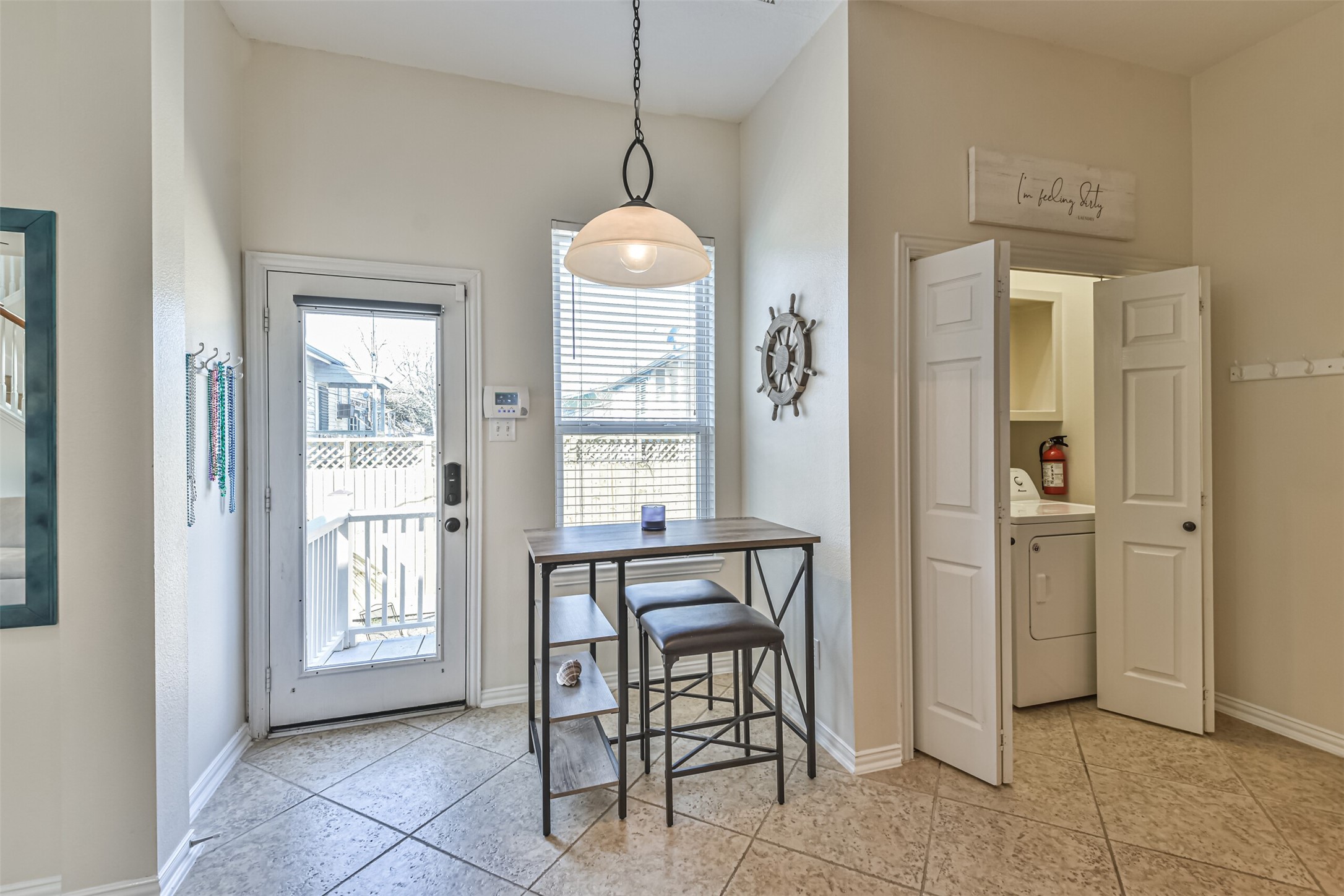 1815 28th Street Galveston, TX 77550 - Photo 8 of 42 Bright and inviting corner with a small dining area featuring a high table and stools. The space includes a door leading outside, a window for natural light, and a convenient adjacent laundry nook with a washer and dryer.