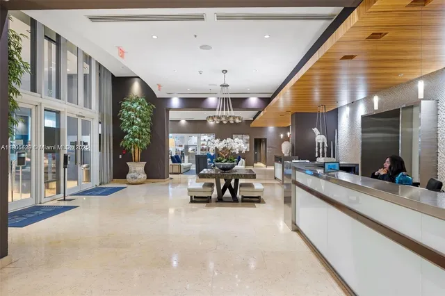 a dining hall with couches a flat tv screen and a dining table with the kitchen view