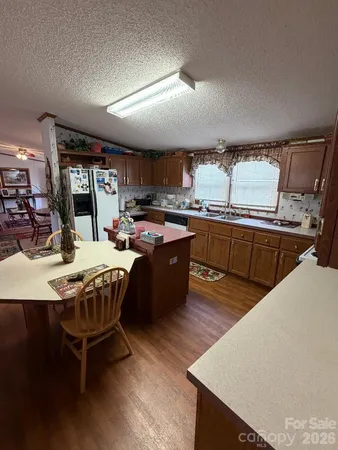 a kitchen with stainless steel appliances granite countertop a stove a refrigerator a sink a dining table and chairs