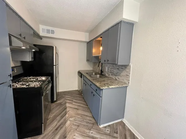 a kitchen with stainless steel appliances granite countertop a sink stove and refrigerator