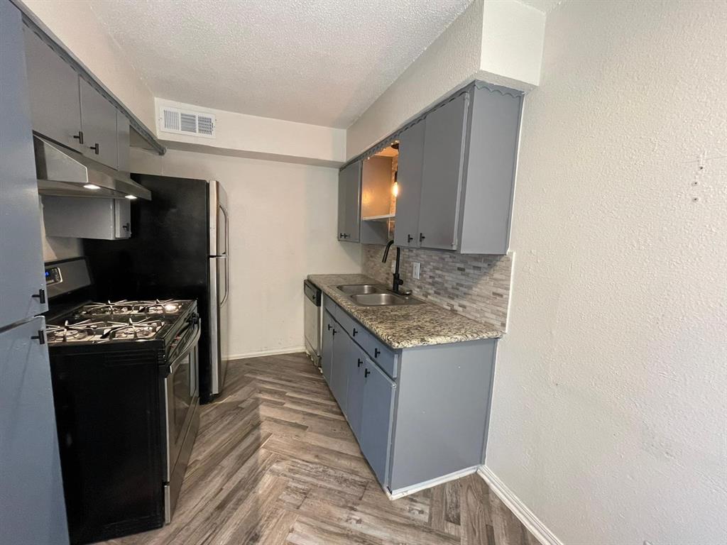 5317 Junius Street, Unit 103 Dallas, TX 75214 - Photo 3 of 6 a kitchen with stainless steel appliances granite countertop a sink stove and refrigerator