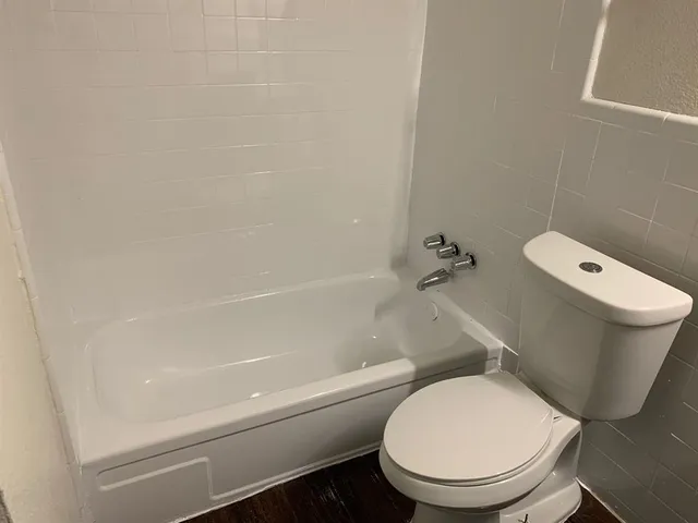 a white toilet sitting next to a bath tub