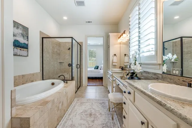 a bathroom with a granite countertop tub double vanity sink and a large mirror