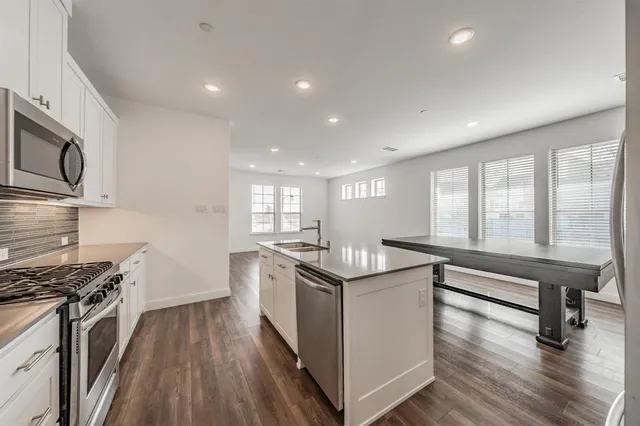 a kitchen with granite countertop cabinets stainless steel appliances and wooden floor