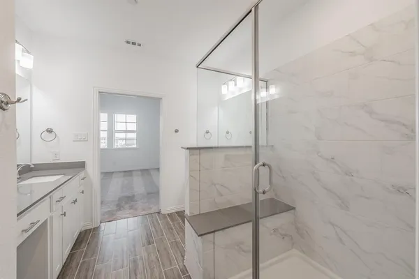 a bathroom with a granite countertop sink a mirror and shower