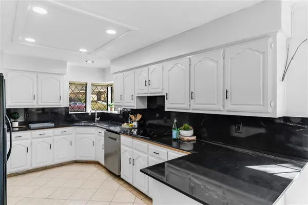 a kitchen with granite countertop a sink a stove and cabinets