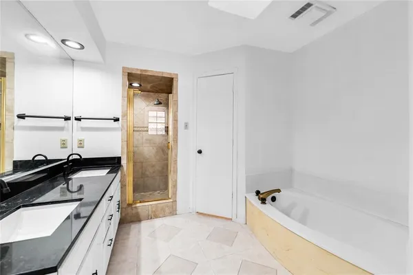 a bathroom with a granite countertop tub sink and mirror
