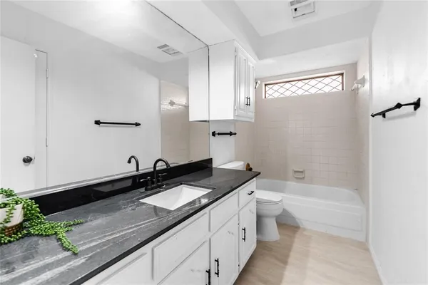 a bathroom with a granite countertop sink a toilet a mirror and bathtub
