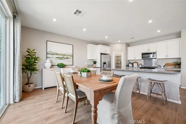 a dining room with stainless steel appliances a table and chairs with wooden floor