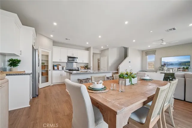 a kitchen with a dining table chairs wooden floor and appliances