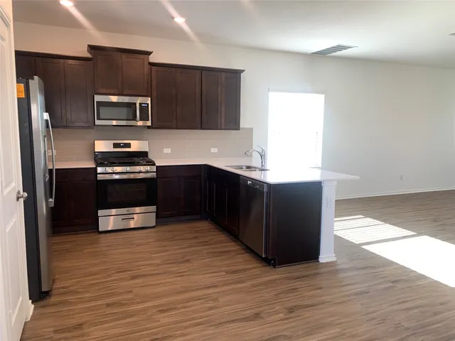 a view of empty room with wooden floor and a window