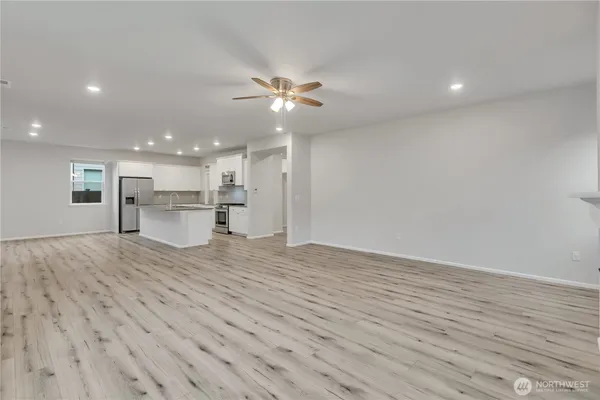 a view of empty room with wooden floor and kitchen view