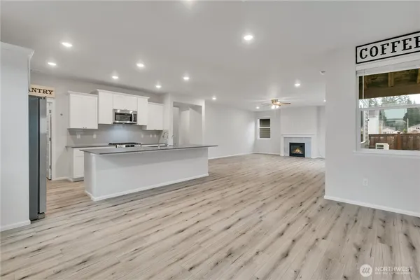 a large kitchen with kitchen island a stove a refrigerator a sink and a oven with wooden floor