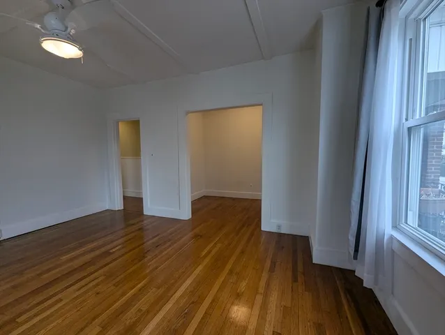a view of wooden floor in an empty room with a window